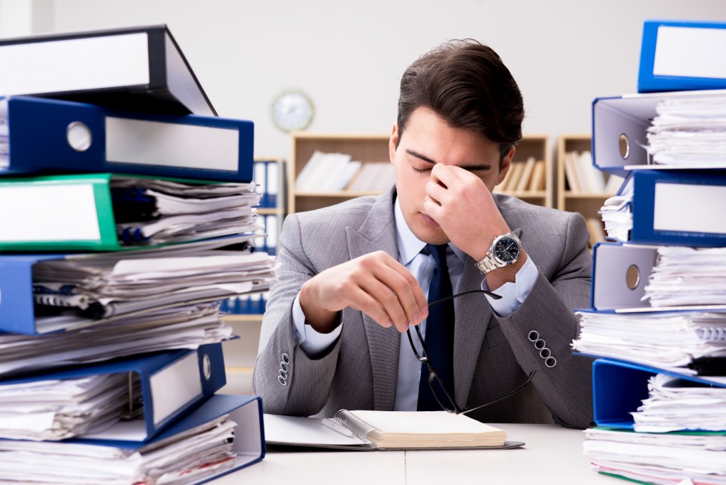 Stressed employee with a lot of paper work on his desk