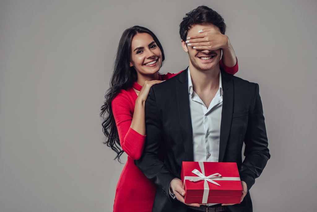 Woman closing eyes of her husband while giving gift
