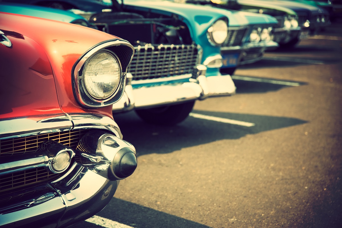 rows of classic cars in a parking lot sepia toned